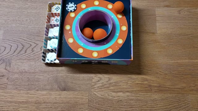 Zwei orangene Bälle landen im Loch der Bounce-It-Box