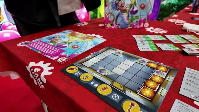 Spielplan und Plättchen von Professor Boom auf dem Messetisch