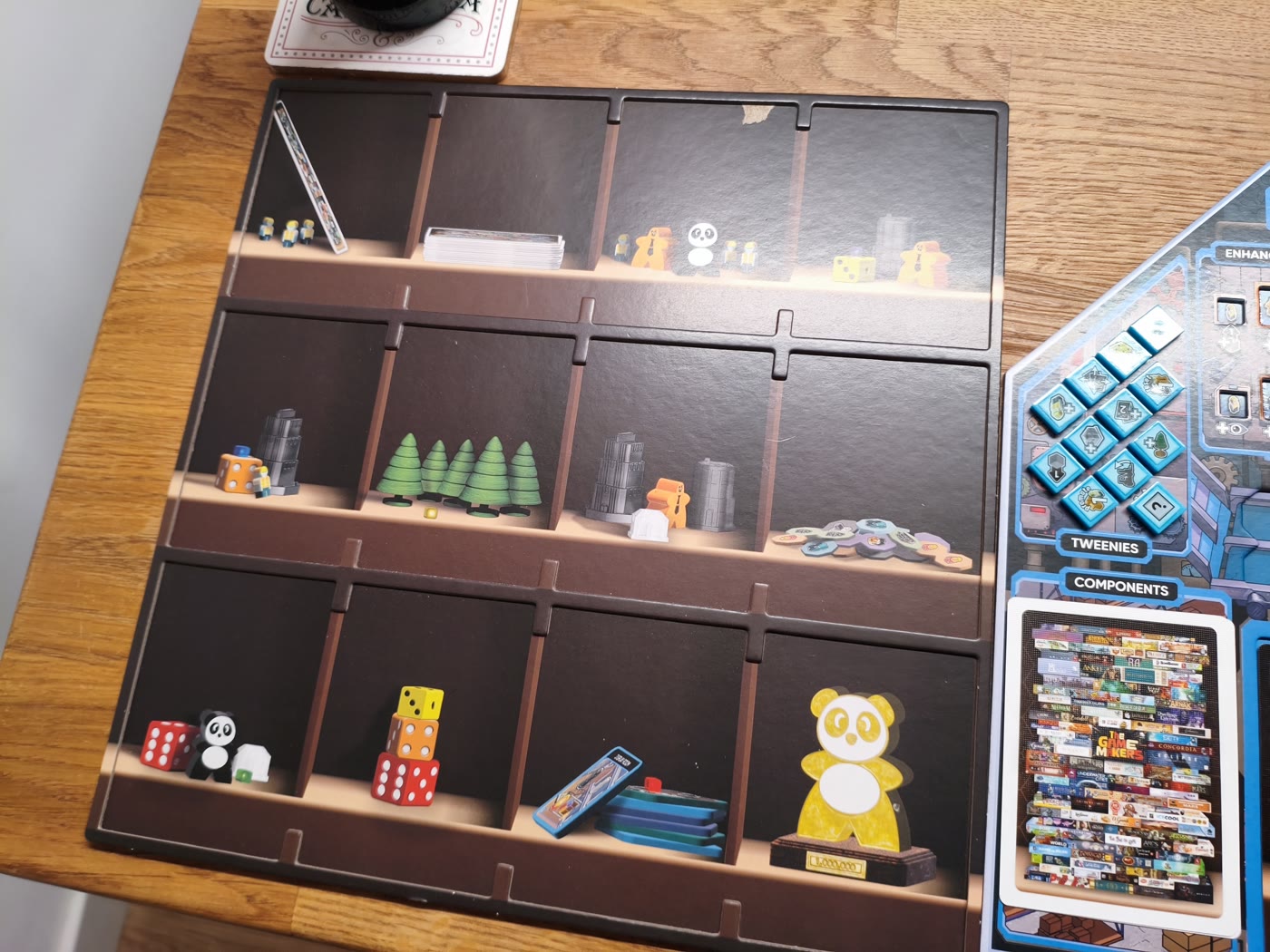 The Game Makers: Lagertableau mit Regalfächern, Würfeln, Bäumen und goldenem Panda